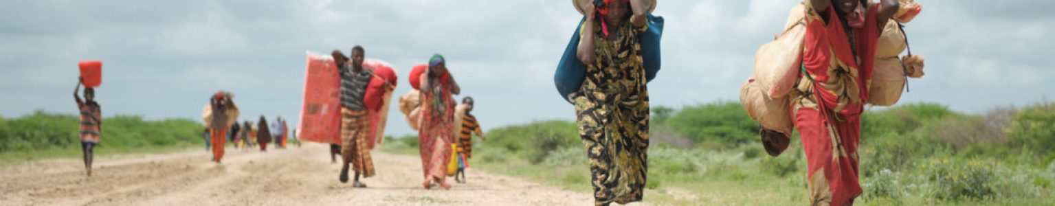 Women, walking with what possesions they can carry, arrive in a steady trickle at an IDP camp erected next to an AMISOM military base near the town of Jowhar, Somalia, on November 12. Heavy rains in Somalia, coupled with recent disputes between clans, has resulted in over four thousand IDPs seeking shelter at an AMISOM military base near the town of Jowhar, with more arriving daily. AU UN IST Photo / Tobin Jones. Original public domain image from Flickr